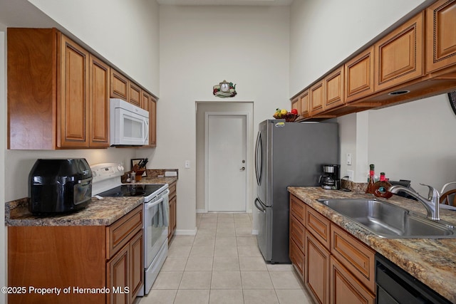 kitchen with sink, white appliances, light tile patterned floors, and a high ceiling