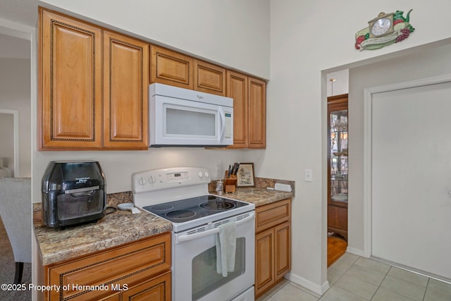 kitchen with light stone counters, light tile patterned floors, and white appliances