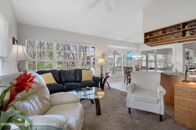 tiled living room with ceiling fan, sink, and a textured ceiling