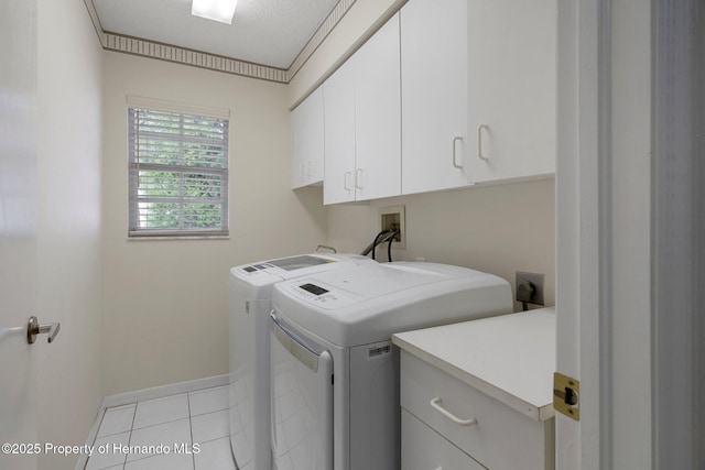 clothes washing area featuring independent washer and dryer, light tile patterned floors, ornamental molding, and cabinets