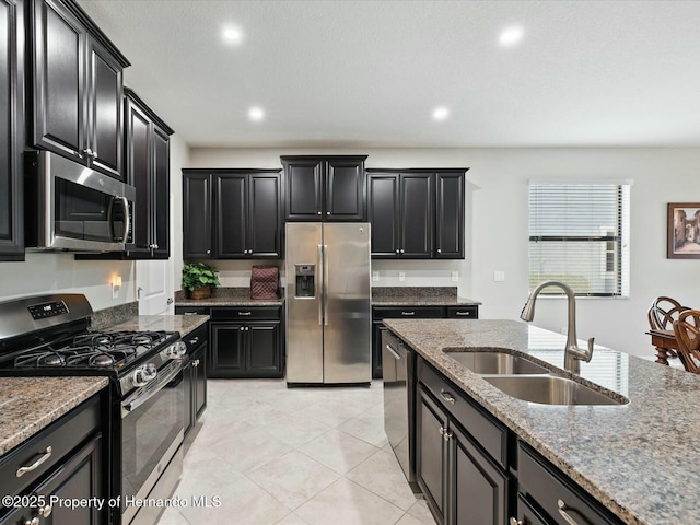 kitchen featuring appliances with stainless steel finishes, sink, light tile patterned floors, and light stone counters