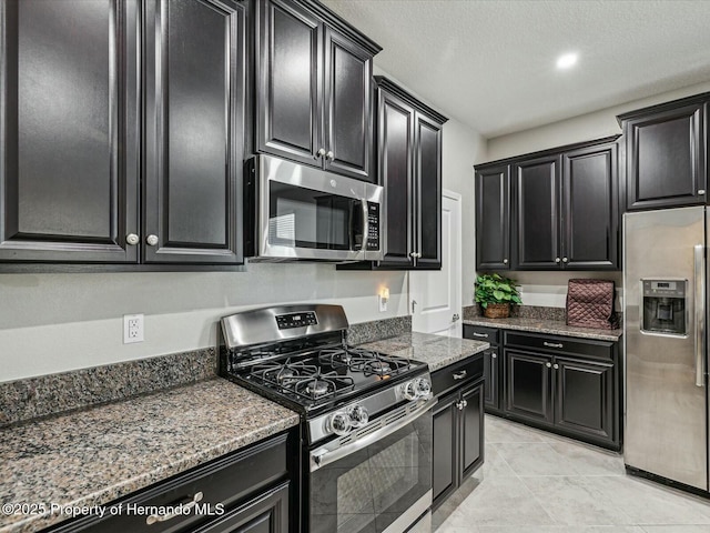 kitchen with dark stone countertops, stainless steel appliances, and a textured ceiling