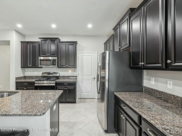 kitchen featuring dark stone countertops, sink, stainless steel appliances, and a textured ceiling