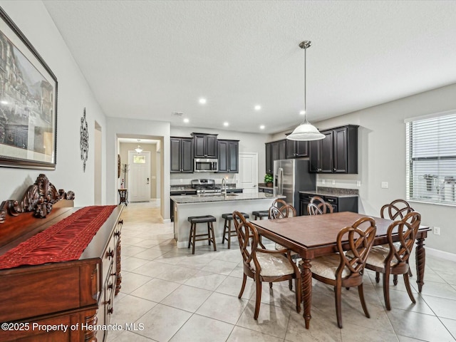 dining room with sink, a textured ceiling, and light tile patterned floors