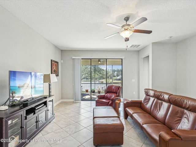 living room featuring light tile patterned floors, a textured ceiling, and ceiling fan