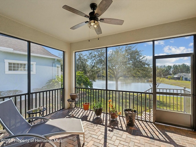 sunroom / solarium featuring a water view and ceiling fan