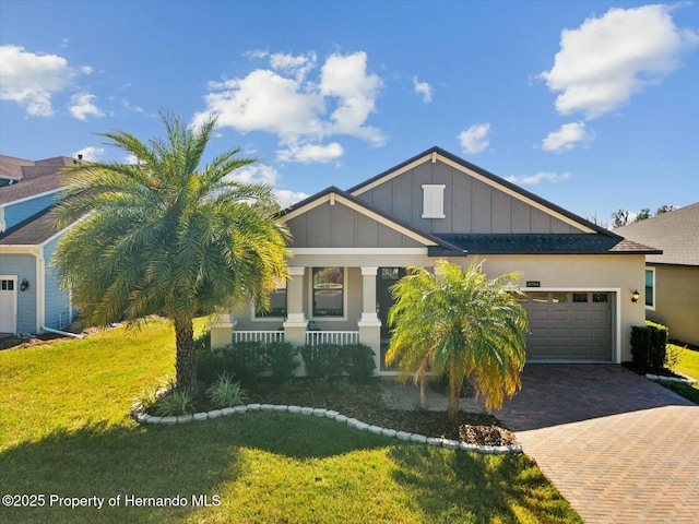 view of front of house featuring a garage, a front yard, and covered porch