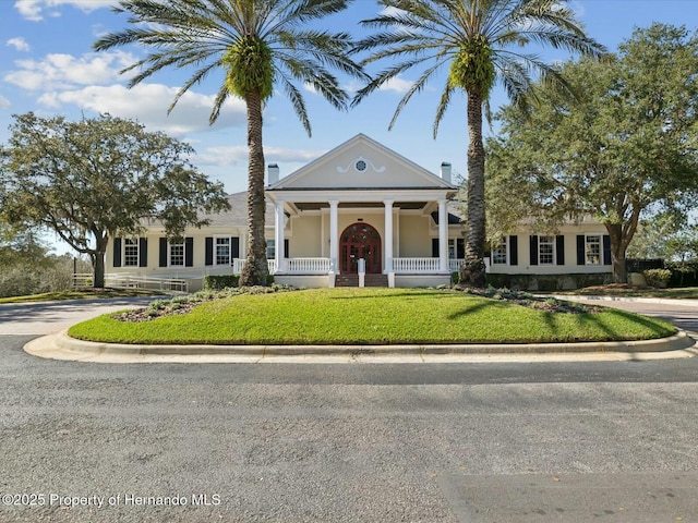 neoclassical home featuring a front lawn and a porch