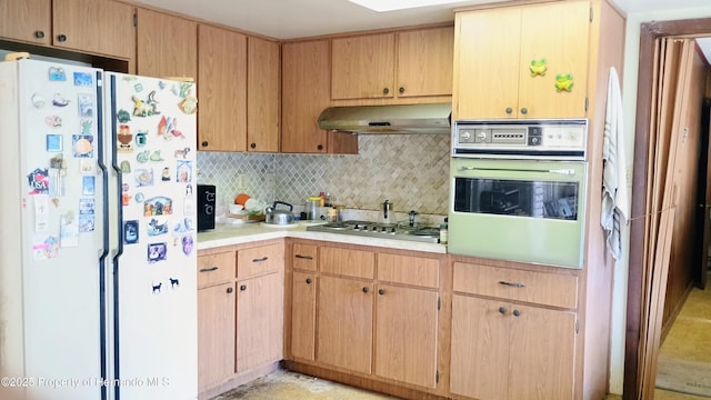 kitchen with white refrigerator, stainless steel gas stovetop, backsplash, and wall oven