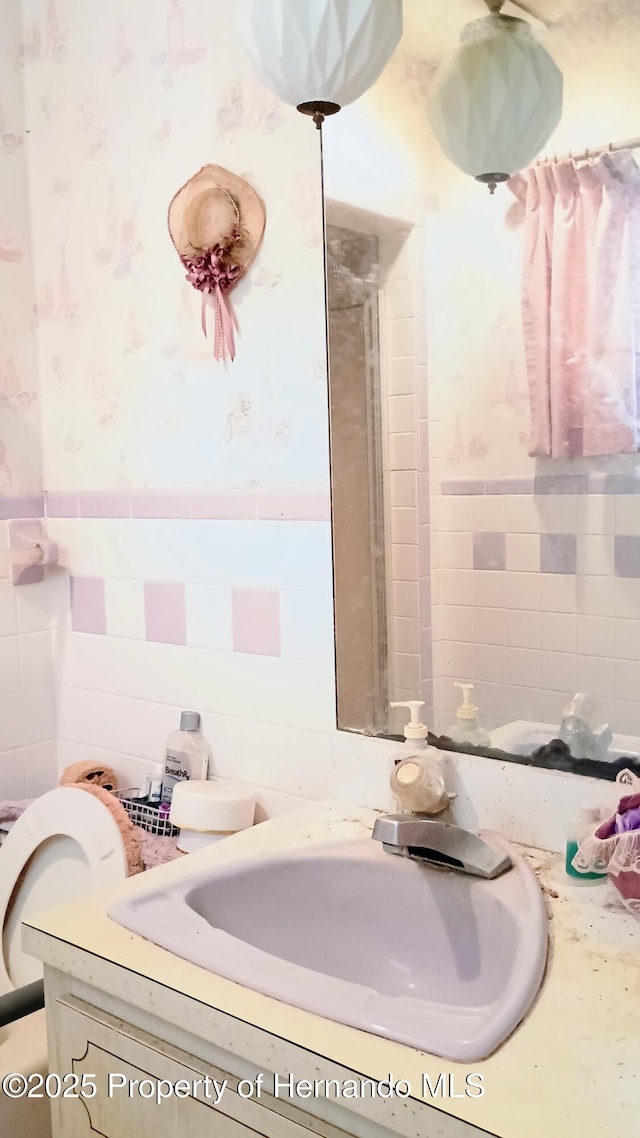 bathroom with a shower, tile walls, and vanity