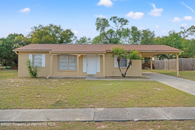 ranch-style house featuring fence, an attached carport, concrete driveway, and a front yard