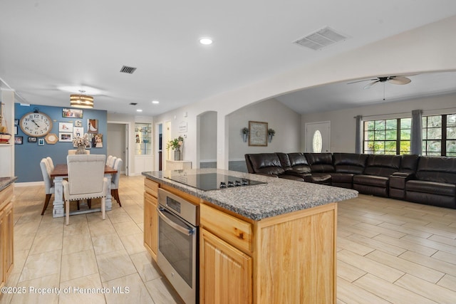 kitchen featuring a kitchen island, oven, black electric stovetop, ceiling fan, and light brown cabinets