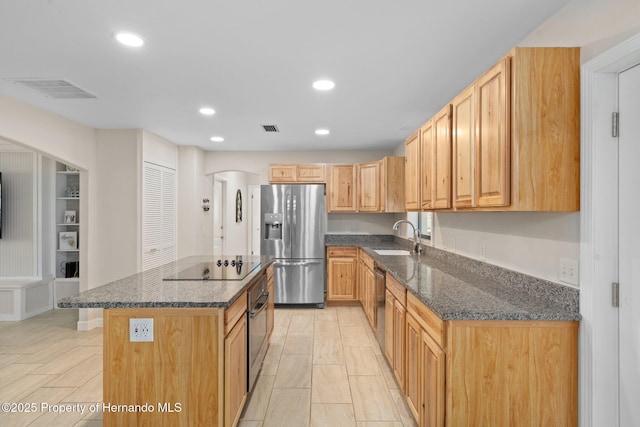 kitchen featuring a kitchen island, appliances with stainless steel finishes, light brown cabinetry, sink, and dark stone counters