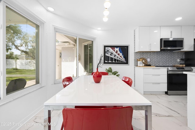 kitchen with white cabinetry, appliances with stainless steel finishes, a breakfast bar, and backsplash