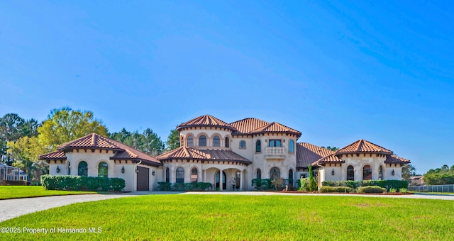 mediterranean / spanish home with driveway, a tile roof, a garage, and a front lawn