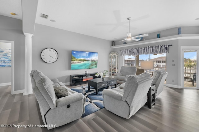 living room with dark hardwood / wood-style flooring, decorative columns, and ceiling fan