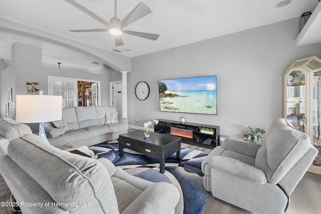 living room featuring ceiling fan, light hardwood / wood-style floors, and ornate columns