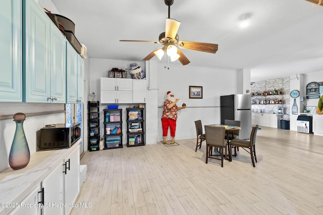 dining space with ceiling fan and light wood-type flooring