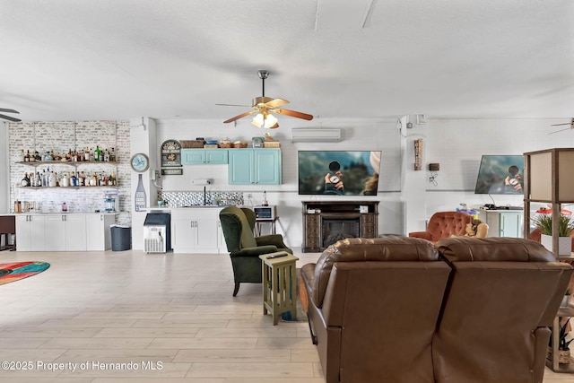 living room with a textured ceiling, bar area, ceiling fan, and light hardwood / wood-style floors