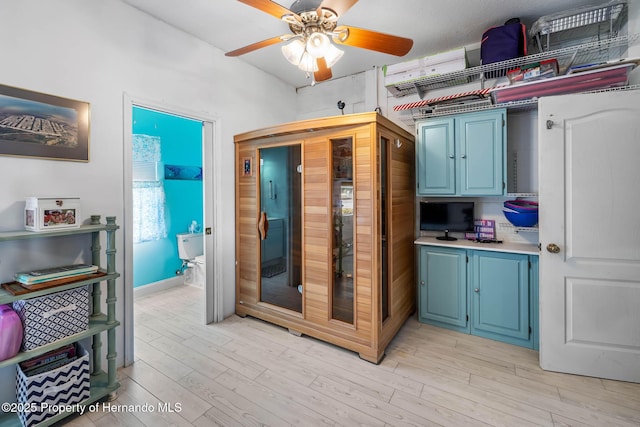 kitchen featuring ceiling fan, blue cabinets, and light hardwood / wood-style floors