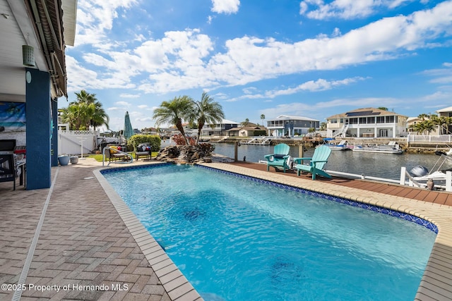 view of swimming pool featuring a water view, a dock, and a patio