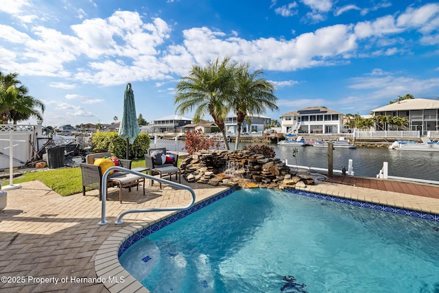 view of pool featuring a patio, a water view, and a dock