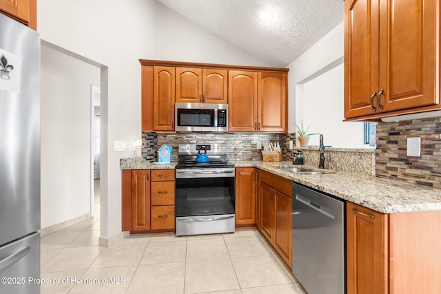 kitchen featuring appliances with stainless steel finishes, sink, light tile patterned floors, and light stone counters