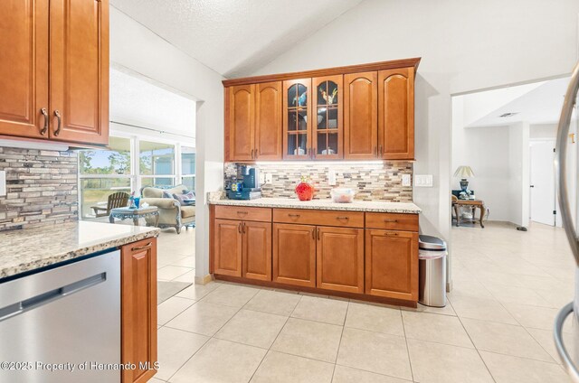 kitchen featuring light tile patterned flooring, lofted ceiling, dishwasher, light stone countertops, and decorative backsplash