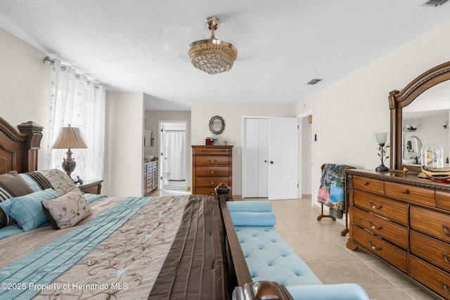 tiled bedroom with connected bathroom and a textured ceiling