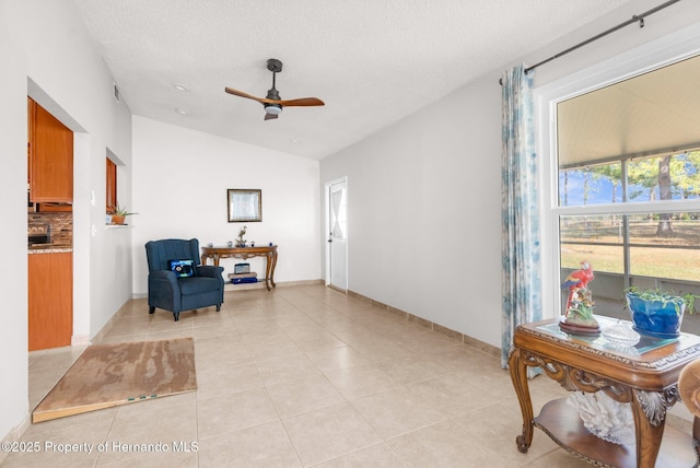 living area with light tile patterned floors, vaulted ceiling, a textured ceiling, and ceiling fan