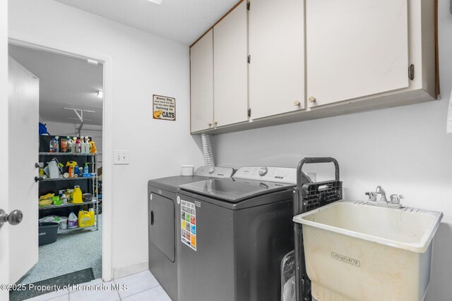 washroom featuring sink, light tile patterned floors, washing machine and dryer, and cabinets