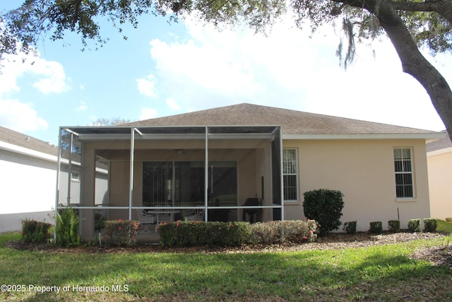 rear view of house featuring a lanai and a lawn