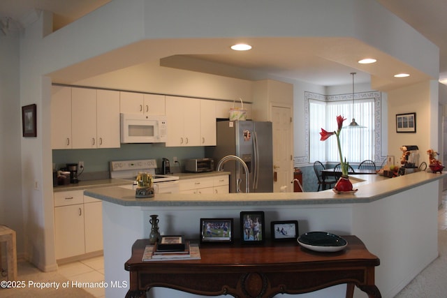 15033 Middle Fairway Dr, Spring Hill, FL 34609 - kitchen with light tile patterned flooring, a center island with sink, a kitchen breakfast bar, white appliances, and white cabinets