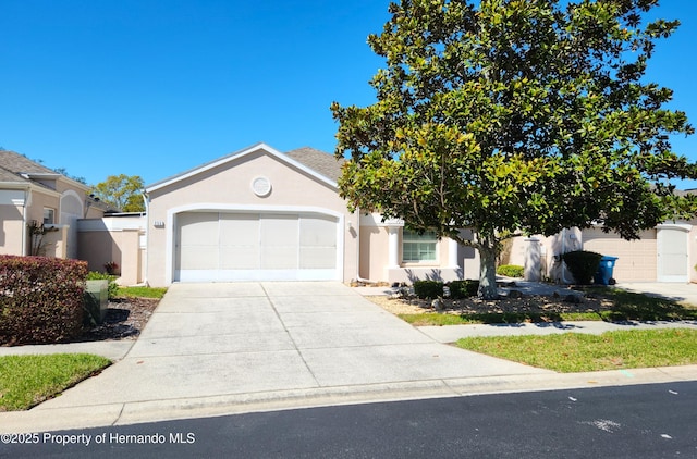 view of front of house featuring stucco siding, concrete driveway, and an attached garage