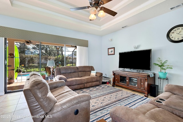 tiled living room with crown molding, ceiling fan, and a raised ceiling