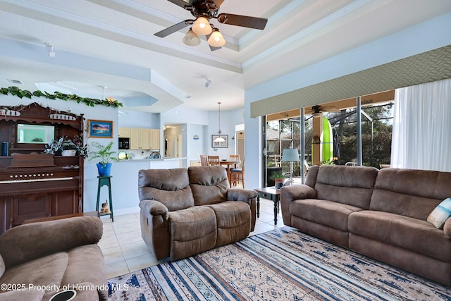 tiled living room with ornamental molding, a raised ceiling, and ceiling fan