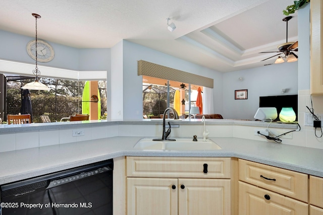 kitchen featuring dishwasher, sink, hanging light fixtures, ceiling fan, and a raised ceiling