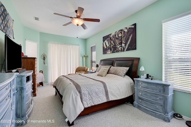 bedroom featuring multiple windows, light colored carpet, and ceiling fan