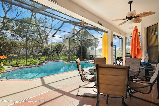 view of swimming pool with ceiling fan, a patio, and glass enclosure