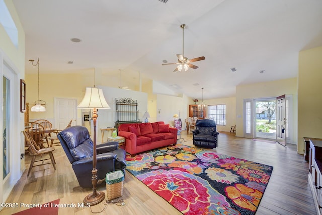 living room featuring hardwood / wood-style flooring, ceiling fan with notable chandelier, and high vaulted ceiling