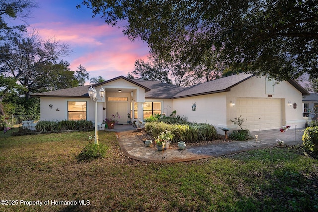 ranch-style home featuring a garage and a lawn