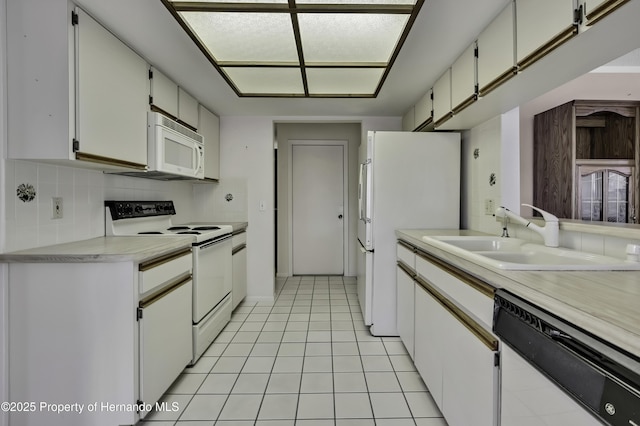 kitchen featuring sink, white appliances, light tile patterned floors, white cabinetry, and backsplash