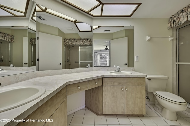 bathroom with tile patterned floors, toilet, a shower with shower door, a skylight, and vanity