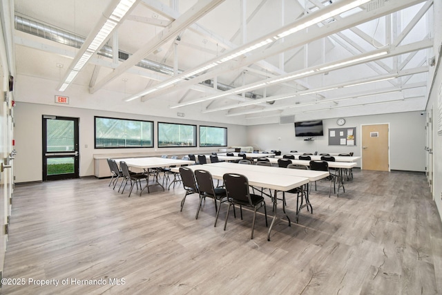 dining area featuring a towering ceiling and wood-type flooring