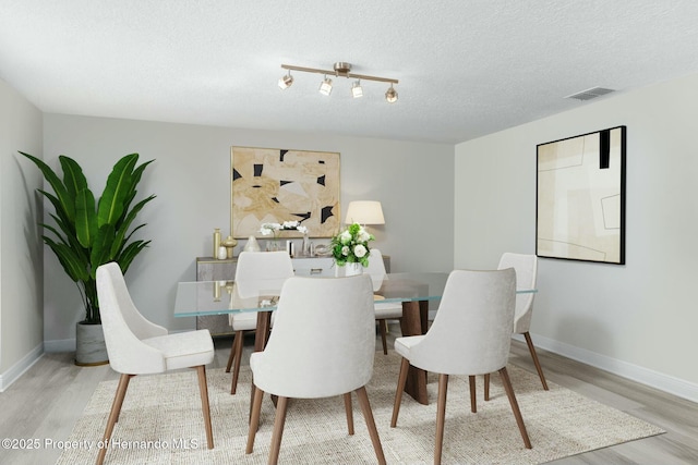 dining space featuring baseboards, wood finished floors, and visible vents