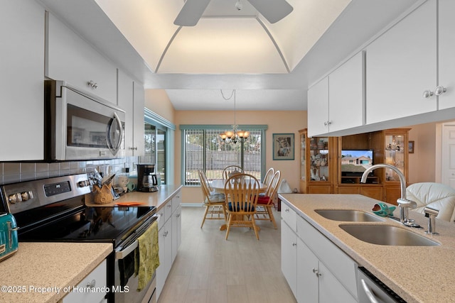 kitchen featuring appliances with stainless steel finishes, pendant lighting, white cabinetry, sink, and backsplash