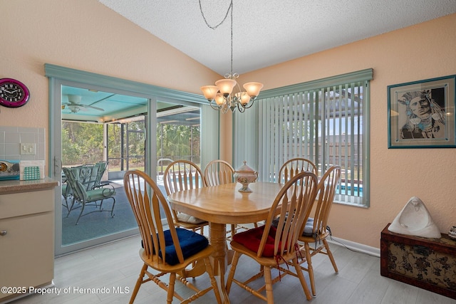 dining space featuring lofted ceiling, a chandelier, a textured ceiling, and light hardwood / wood-style floors