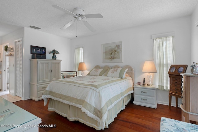 bedroom with dark hardwood / wood-style flooring, ceiling fan, a closet, and a textured ceiling