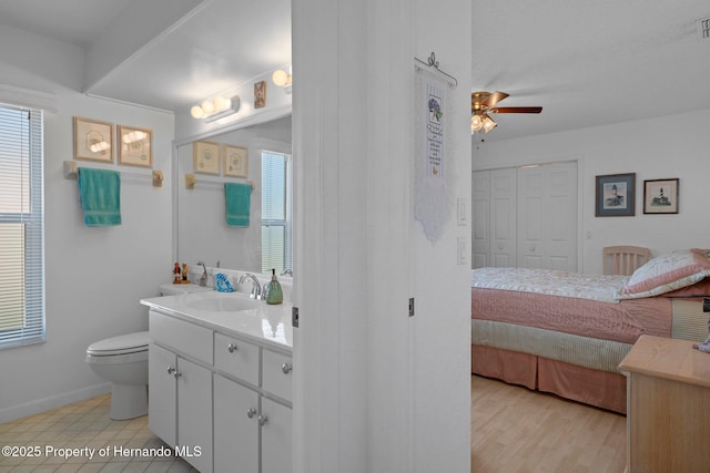 bathroom with ceiling fan, a healthy amount of sunlight, toilet, and vanity