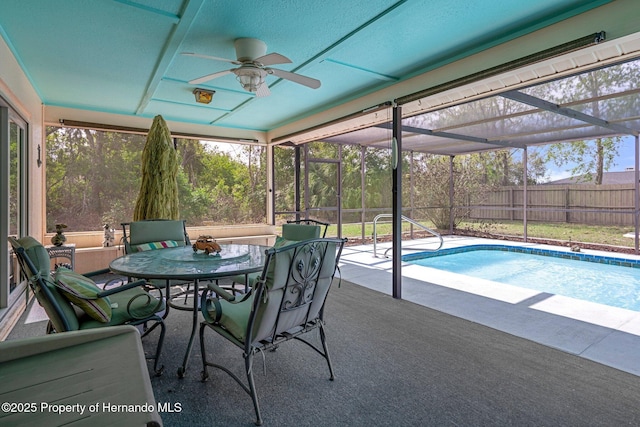 view of swimming pool with ceiling fan, a patio area, and glass enclosure